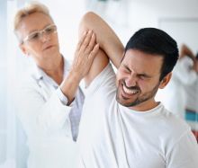 Eine Ärztin behandelt einen Mann wegen Rückenschmerzen.
